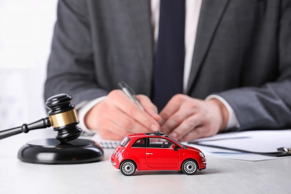 A lawyer reviews a car accident settlement offer at a desk with a model car.