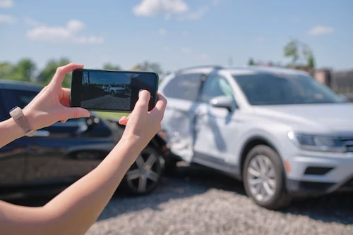 A driver taking photos represents what to do after a car accident in Houston.